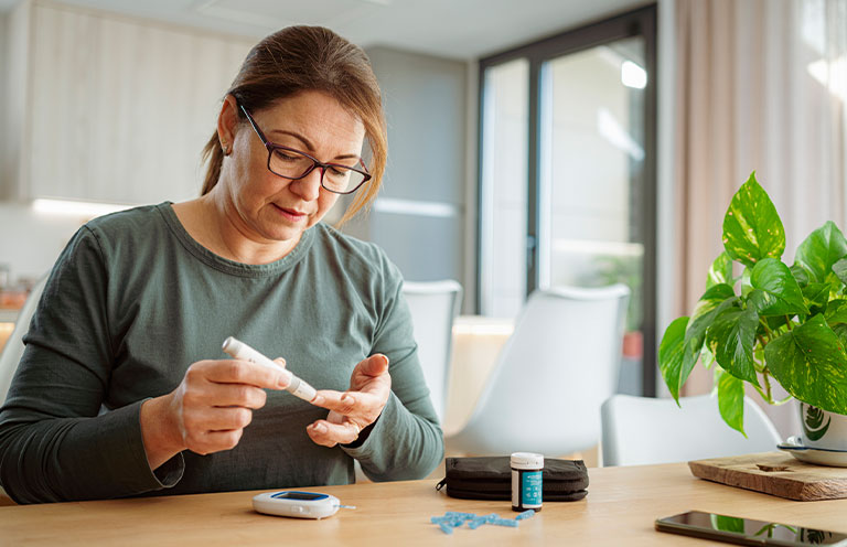 diabetic woman using lancet on finger for checking blood sugar level by Glucose meter