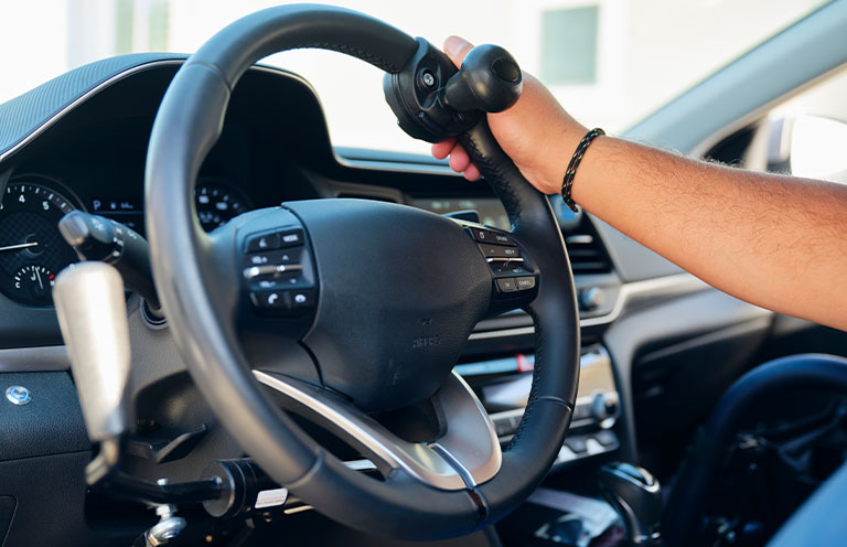 A disabled man in the driver seat of a car modified to drive with hands only