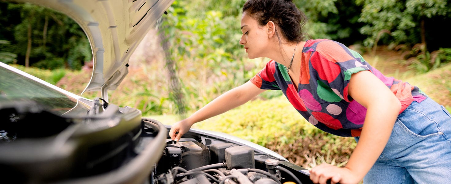 woman looking at car battery under hood