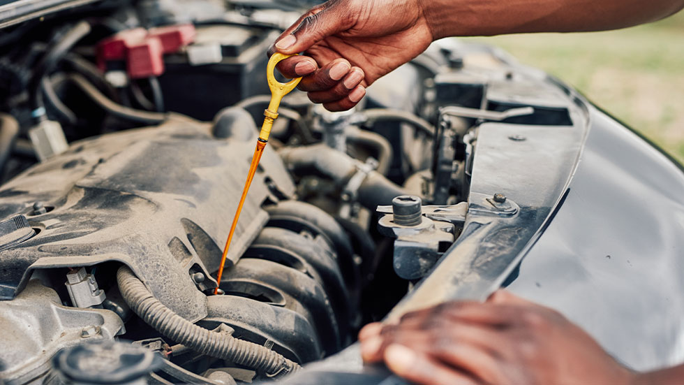 man checking oil levels in his car with dipstick