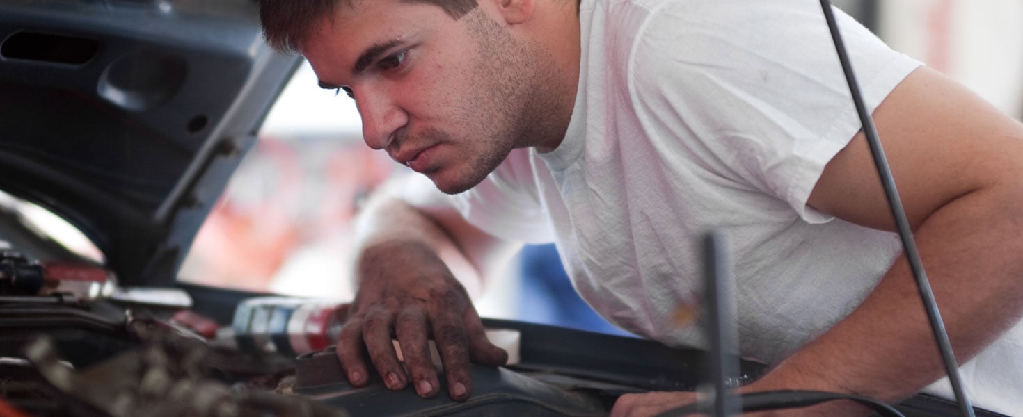 man looking under the hood of car