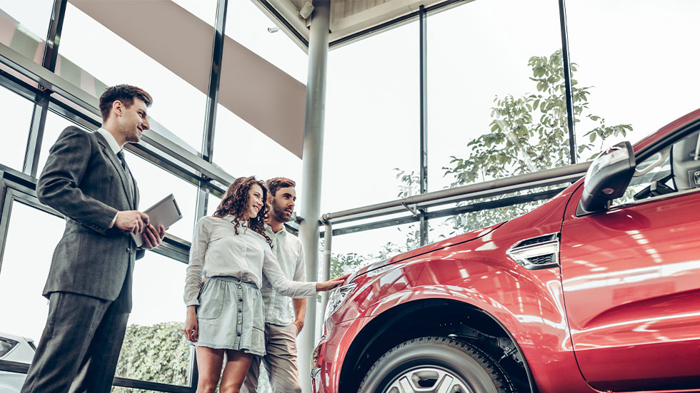 couple looking at car with salesman