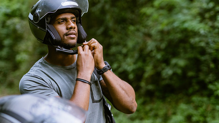 Biker putting on helmet in nature park