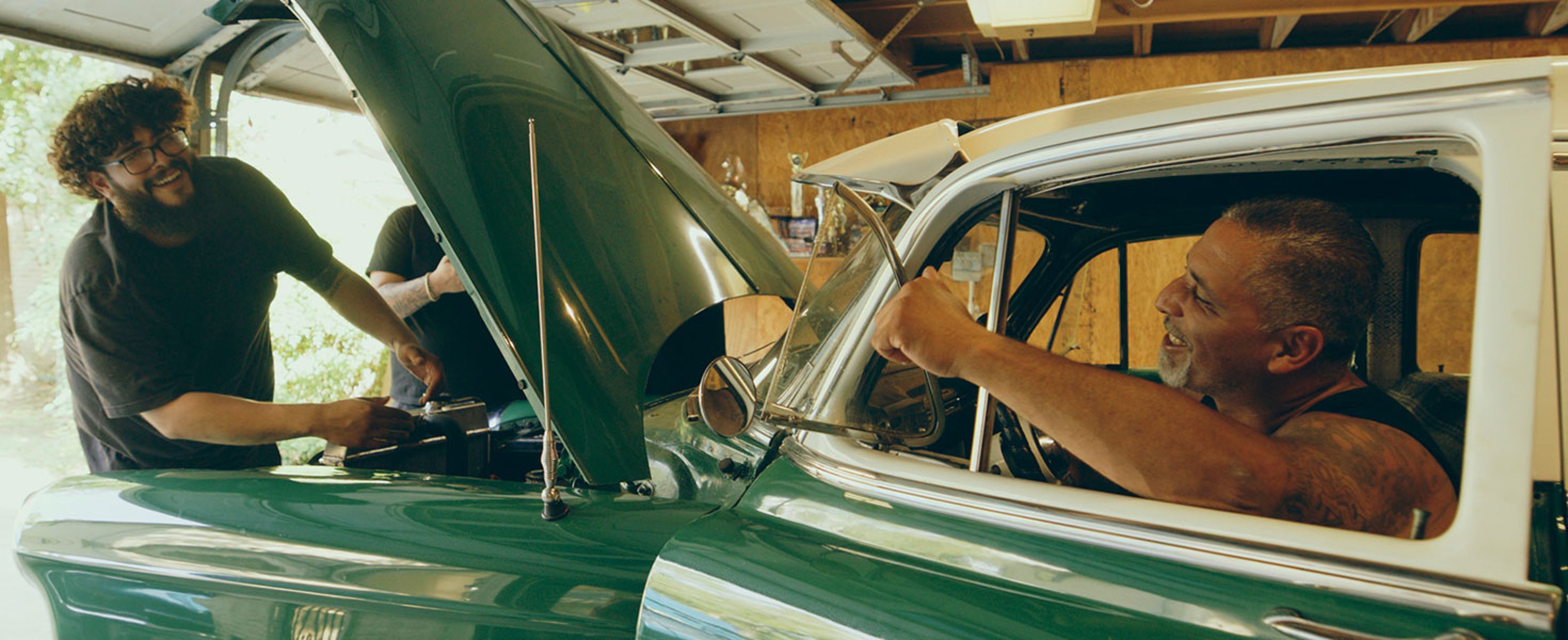 A hispanic father and sons working on a vintage car in a home garage. Credit:O2O Creative