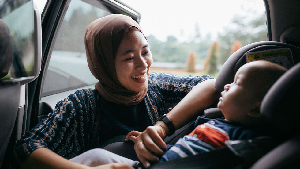 mom putting baby in car seat