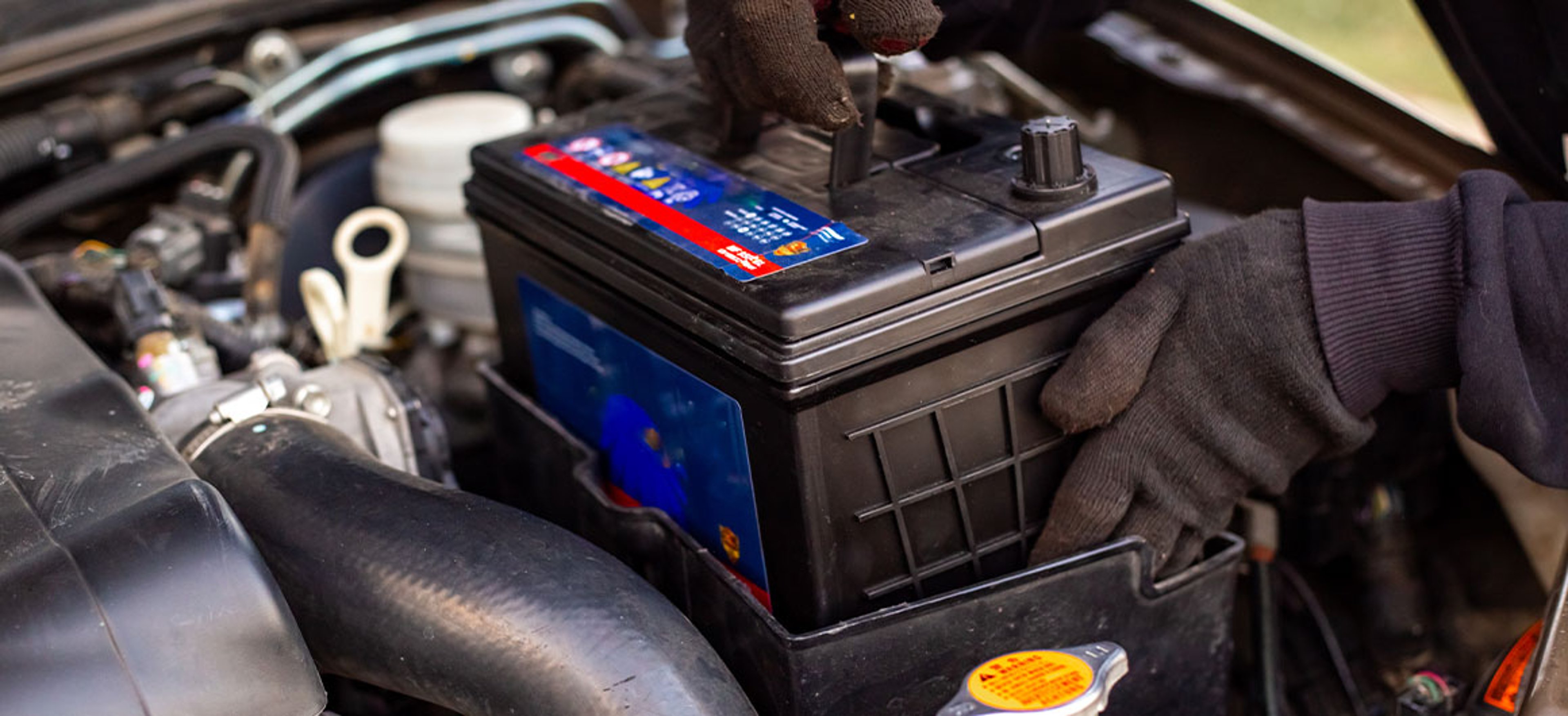 man putting car battery in car