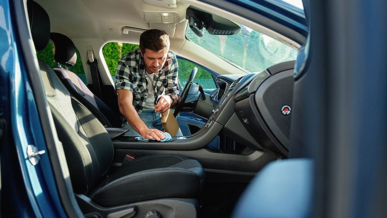 Man cleaning car interior with microfiber cloth and spray. Concept of auto maintenance, disinfection and vehicle hygiene Credit:Lazy_Bear