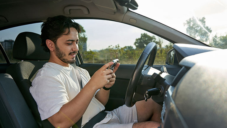 young man playing on the phone in the car Credit: canart7