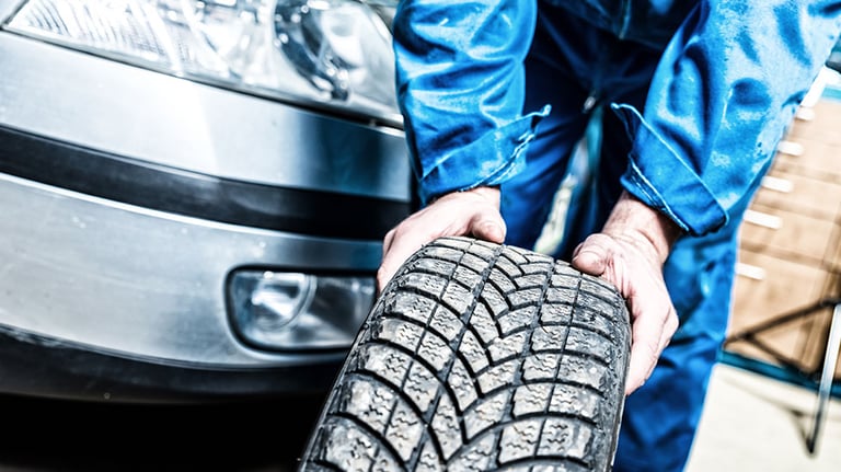 Mechanic fixing tyre in car service. Credit: GregorBister