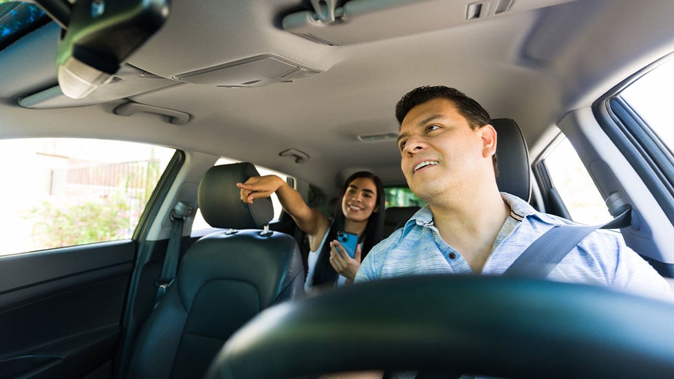 driver following a gps route while passenger shows directions on a smartphone app in a rideshare service