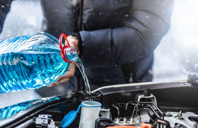 man addin windshield wiper fluid to car