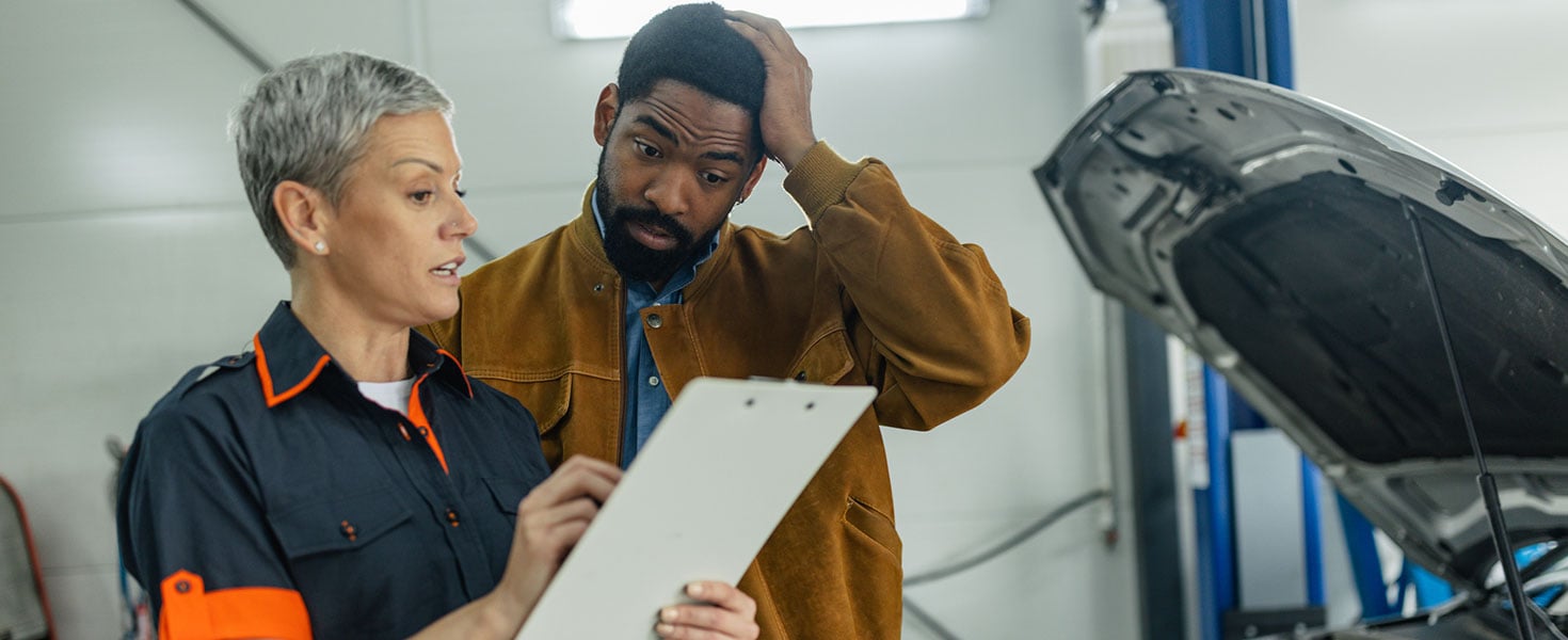 The woman mechanic explains a technical issue to a man, who appears concerned and engaged, highlighting the importance of clear communication in the automotive repair process. Credit:supersizer
