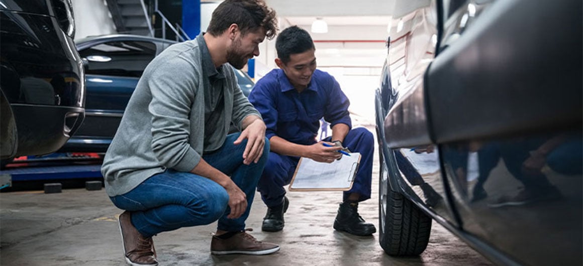 men looking at car's tire in a repair shop