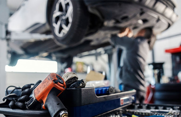 men looking at car's tire in a repair shop