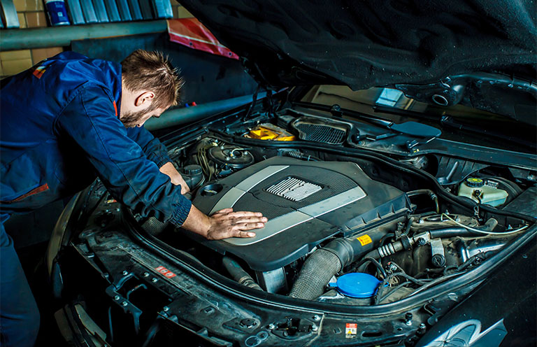 man looking under hood of car