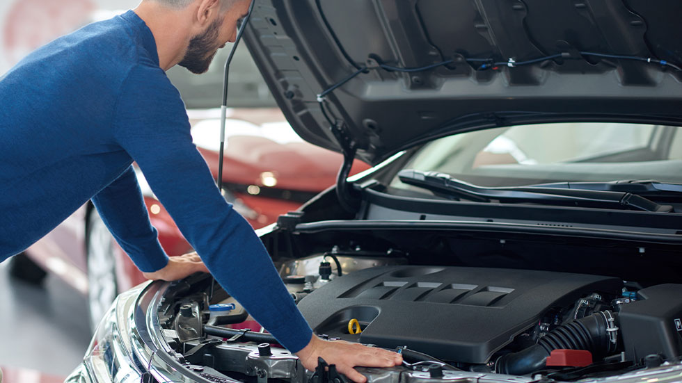 man looking under hood of a car