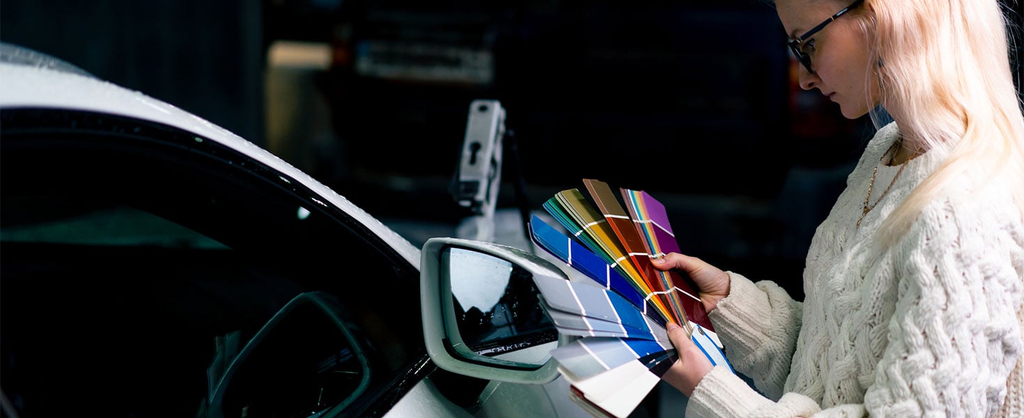 Woman with paint pallet tester choosing new color for car