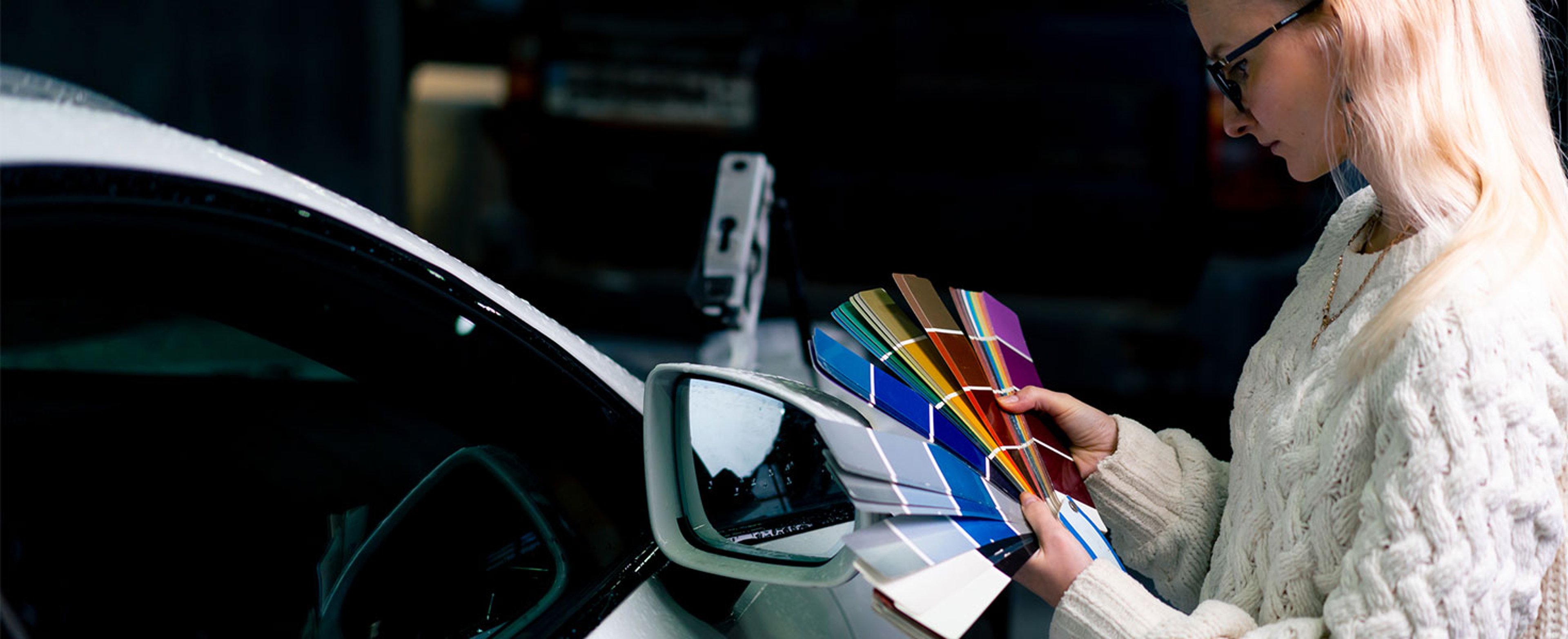 Woman with paint pallet tester choosing new color for car