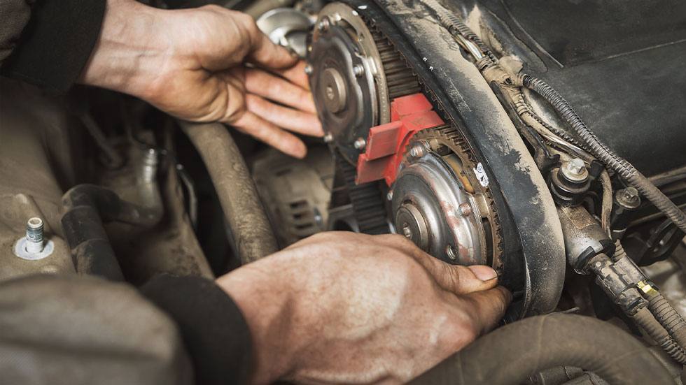 Person changing timing belt in car