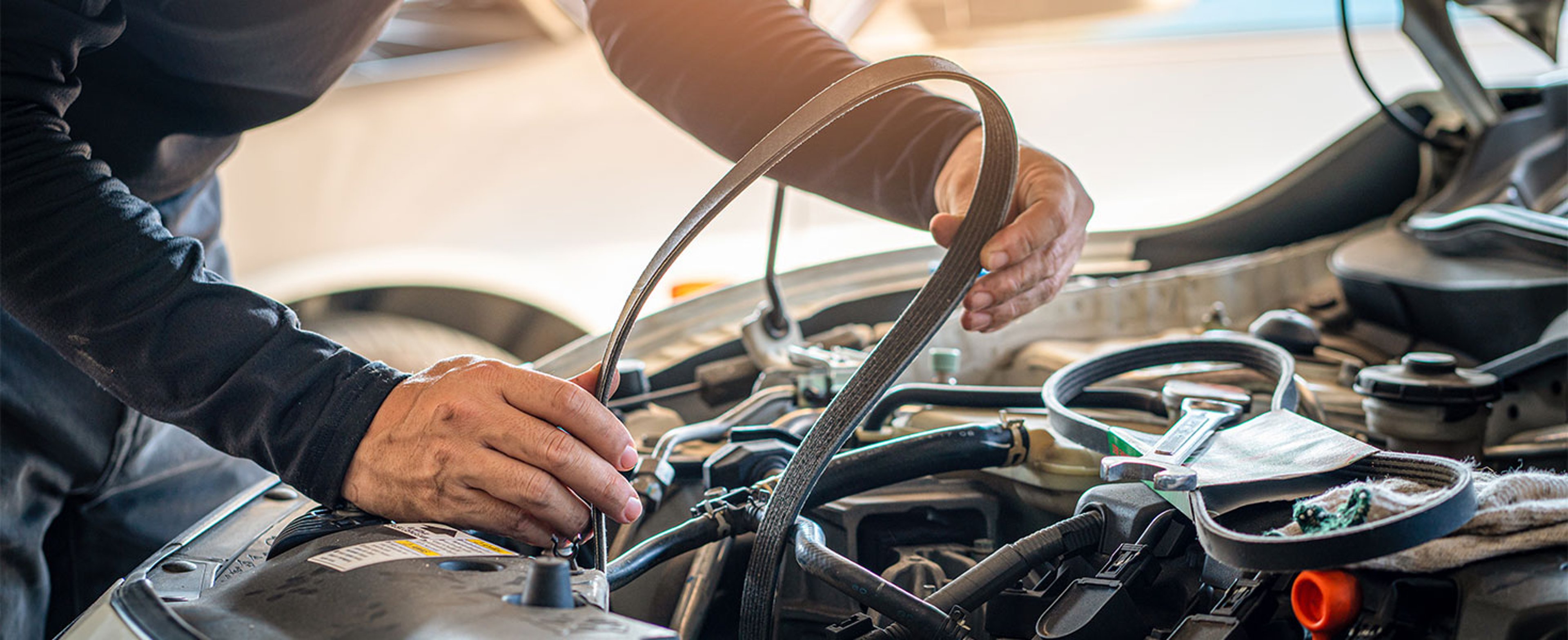 Person changing timing belt in car