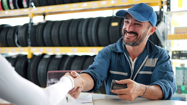 Happy automotive mechanic man in uniform shaking hands with client at auto repair shop. Car service, repair, maintenance, gestures and man mechanic concept. Credit: M Stock