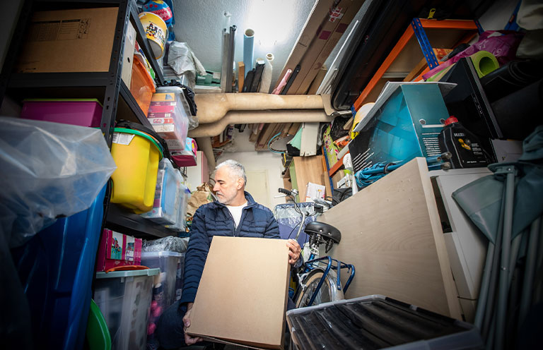 man moving boxes from messy garage