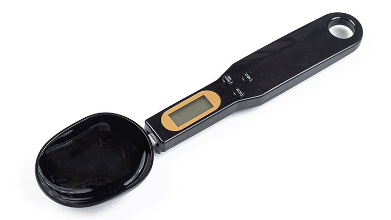 Black spoon scale isolated above white background By zlajaphoto