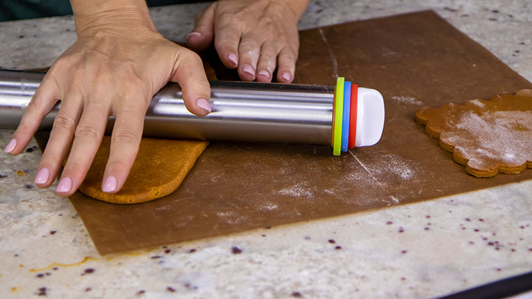 A view of a pastry chef's female hands rolling out dough with a modern metal rolling pin for making ginger cookies. The concept of cooking and baking fragrant desserts. Credit:I am the author of images and videos