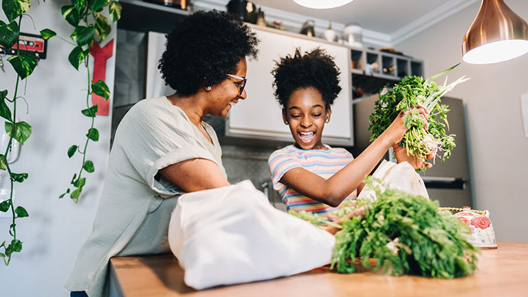Mother and daughter talking and unpacking fruits and vegetables in the kitchen at apartment Credit:FG Trade