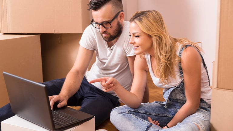 couple sitting in front of boxes looking at laptop