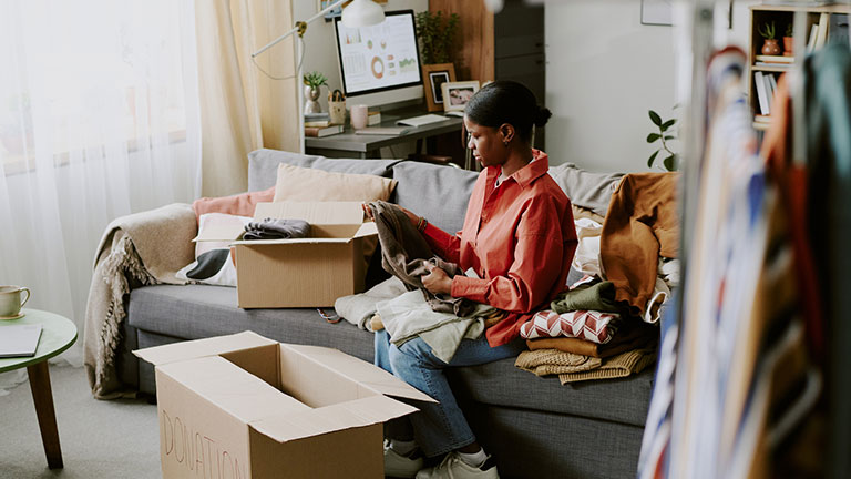 Black Woman Sorting Donated Clothes for Charity Resale Business; Credit: AnnaStills