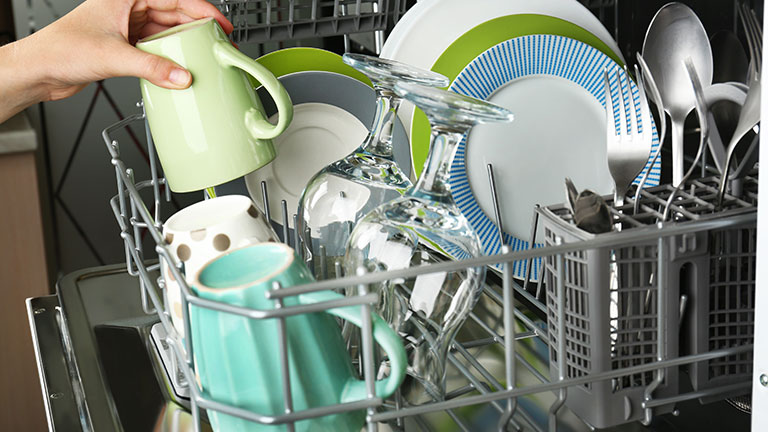 Open dishwasher with clean utensils in it By Africa Studio
