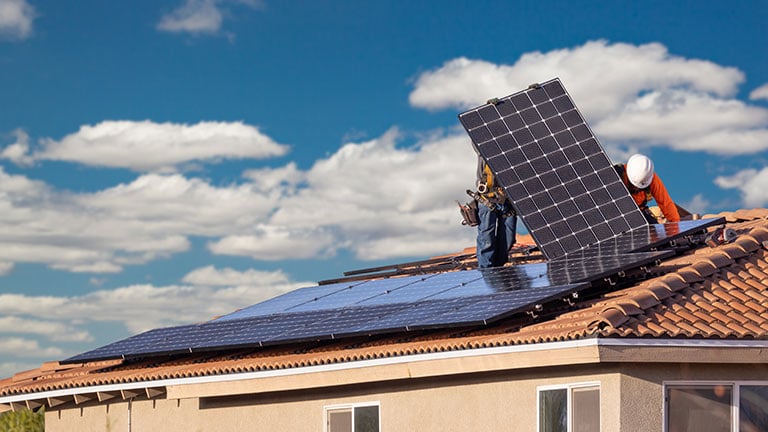 Workers Installing Solar Panels on House Roof By Andy Dean