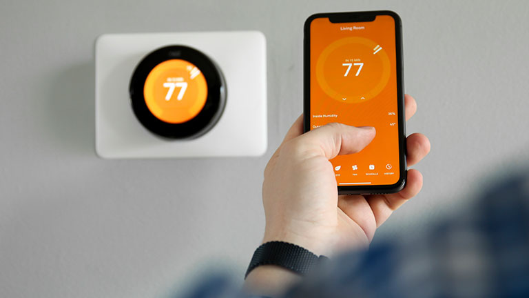 Man uses a mobile phone with smart home app in modern living room
