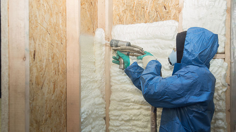 The worker insulates the walls of the house with foam for sound insulation and heat