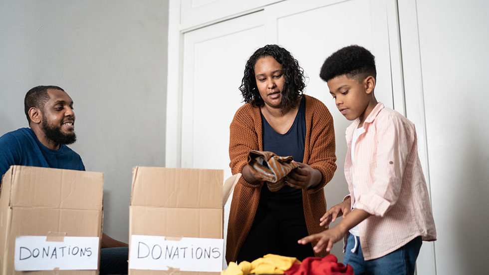 Parents with son sorting out clothes in boxes to donate at home