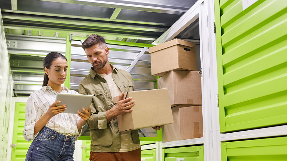 Man and woman looking at digital tablet while loading boxes into self storage unit