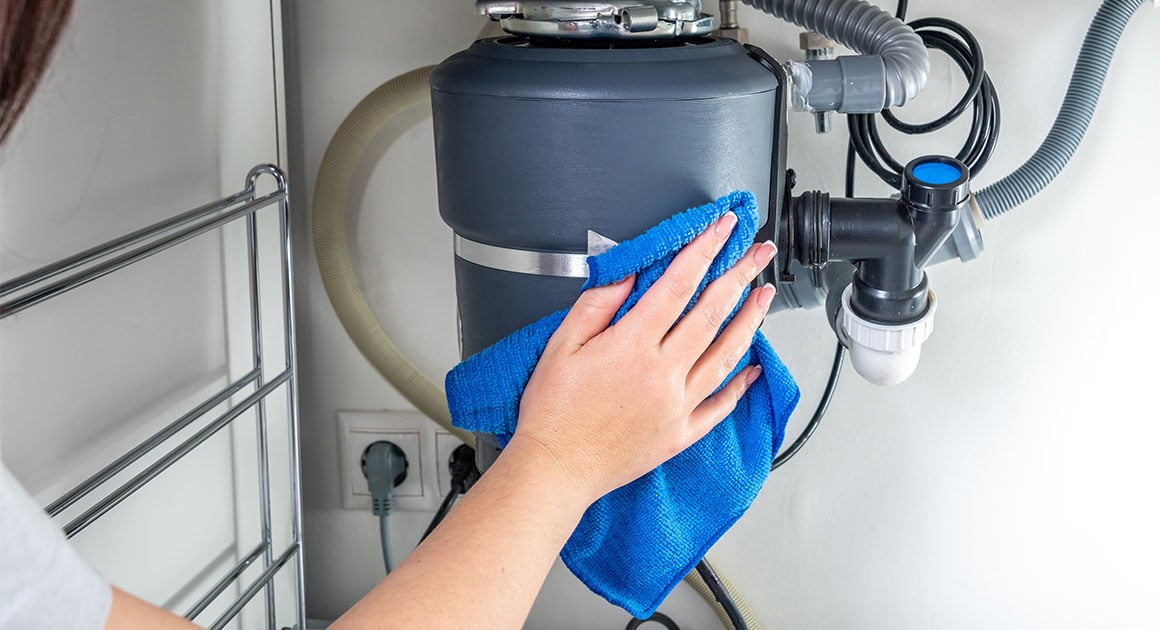person wiping down garbage disposal