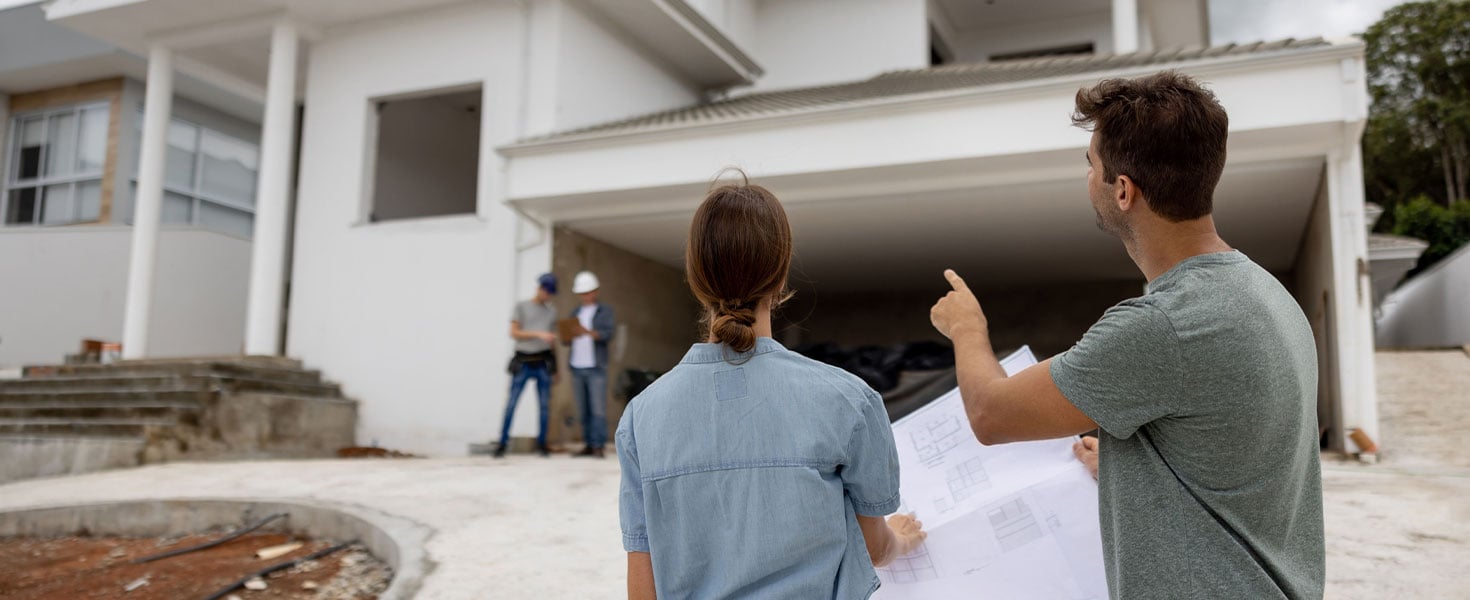 Man and woman talking outside home, holding house plans