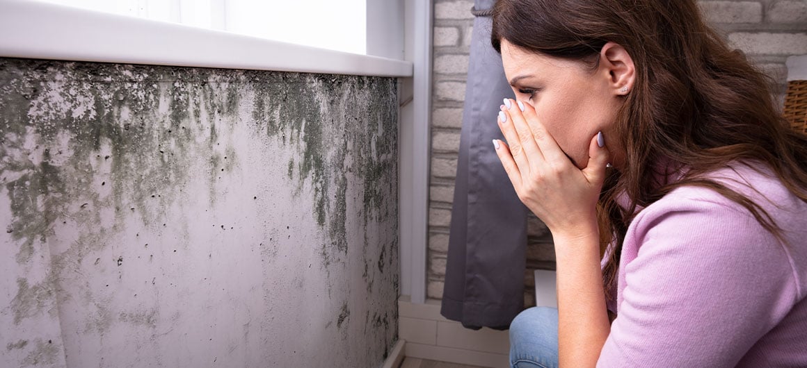 woman looking at mold on wall