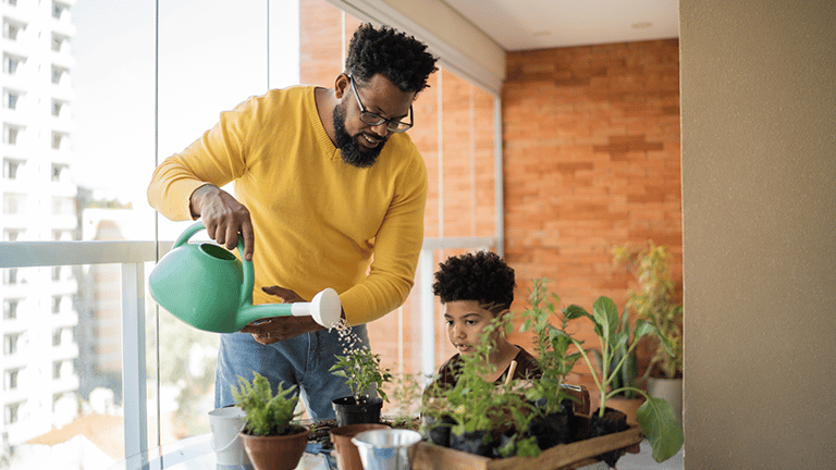 Father and son watering plants at home Credit: FG Trade