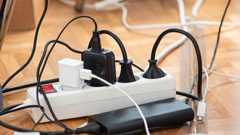 Messy outlet power extension cord on an apartment floor