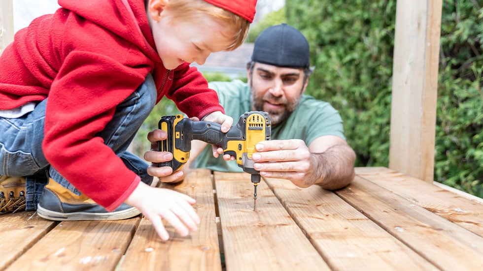 Man showing boy how to use a drill