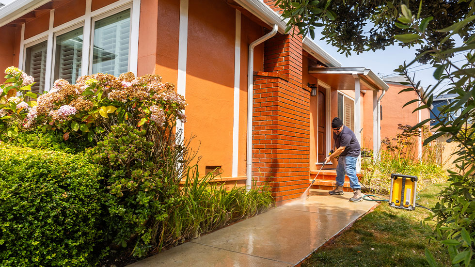 Man pressure washing walkway 