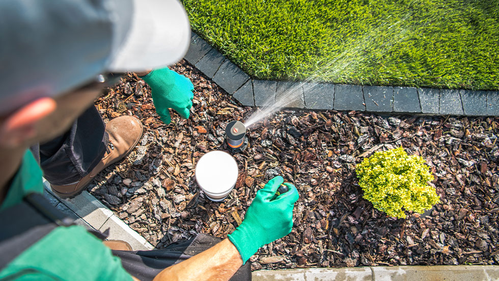 man adjusting lawn sprinkler