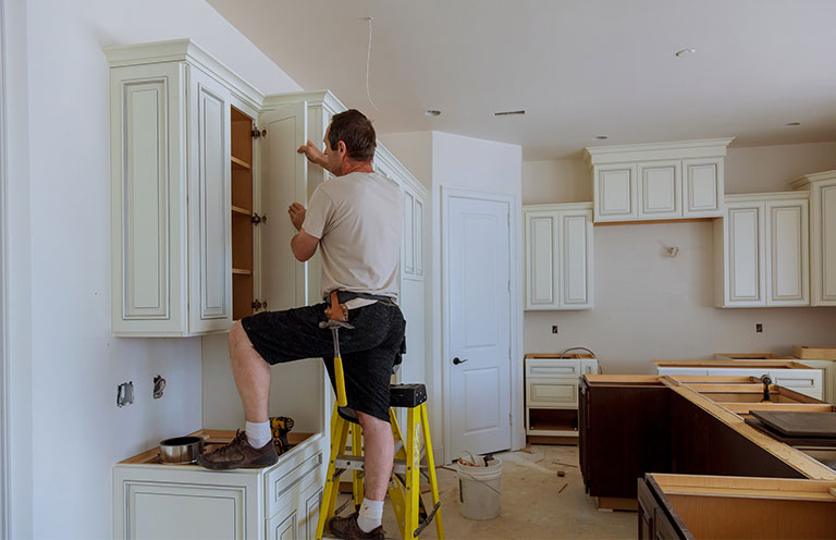 man installing kitchen cabinet doors