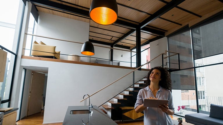 Latin American woman controlling the lights of her house using a home automation system - smart home concepts Credit:andresr