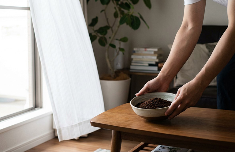 coffee grounds in bowl being placed on table