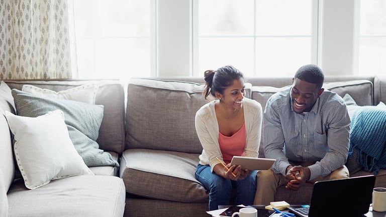 Shot of a young couple going through paperwork together on the sofa at home