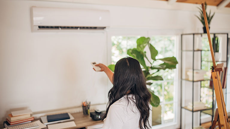 Woman turning on air conditioner; Credit: South_agency